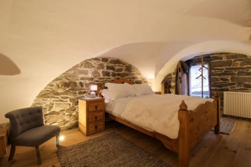 une chambre avec un lit et un mur en pierre dans l'établissement Charmante maison de hameau traditionnel montagnard, à Saint-Marcel