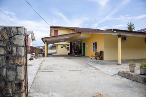 una casa amarilla con una pared de piedra en Sweet Inn Guest House en Kuantan