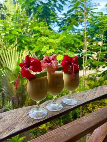three wine glasses with flowers on a wooden rail at ORCHID RESORT Ltd in Guillet
