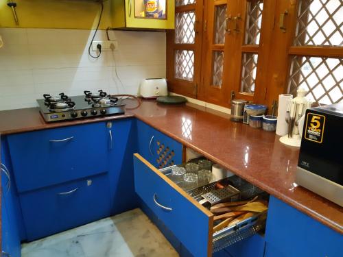 a kitchen with blue cabinets and a stove at LAVISH Fully Furnished HOMESTAY - ISH, Atithya with various free amenities in Lucknow, INDIA in Lucknow