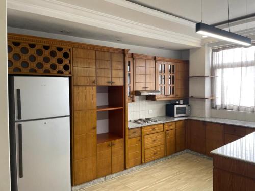 a kitchen with wooden cabinets and a white refrigerator at Geza Apartment Hotel in Addis Ababa