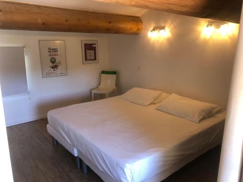 a bedroom with a white bed and a chair at A l'abris des regards au Mas du Soleil in Caumont-sur-Durance