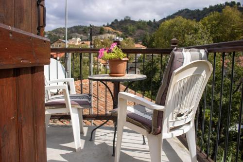 three chairs and a table on a balcony with a pot of flowers at Morfeas Kakopetria in Kakopetria
