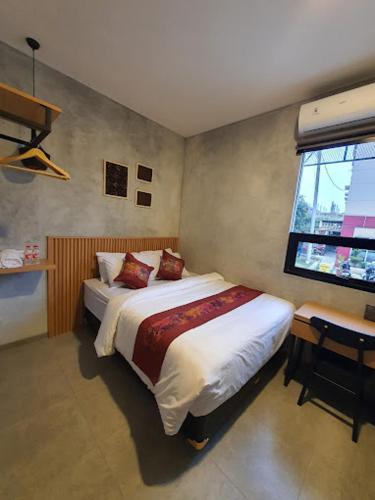 1 dormitorio con cama, escritorio y ventana en The Cluster Harris, en Cimahi