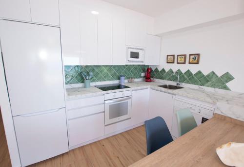 a kitchen with white cabinets and a wooden table at Edificio Calpemar in Calpe