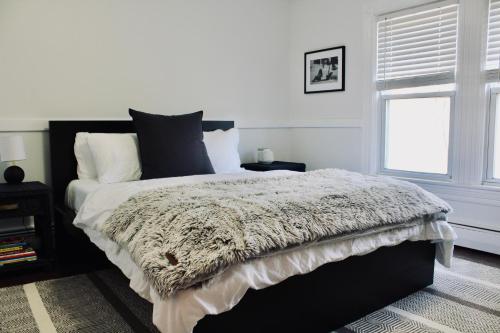 Schlafzimmer mit einem schwarzen und weißen Bett und einem Fenster in der Unterkunft Cozy Ski House Retreat minutes to Belleayre Mountain Resort in Fleischmanns