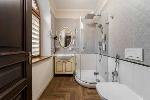 een badkamer met een douche, een bad en een wastafel bij Luxury Boutique Andreevskiy in Lviv