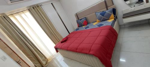 una camera da letto con un letto con una coperta rossa e una finestra di The Taj Studios-2Bhk Flat in North Eye Stay with Friend & Family a Noida