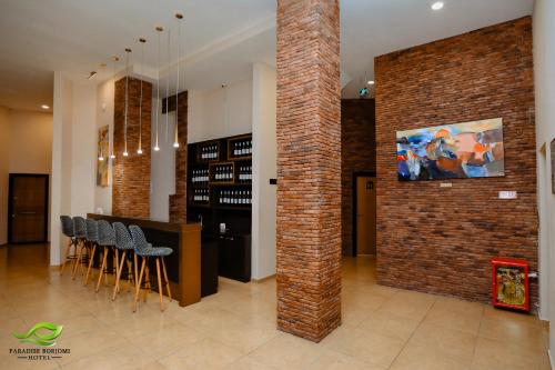 a room with a brick wall and a bar with stools at Paradise Borjomi Hotel in Borjomi