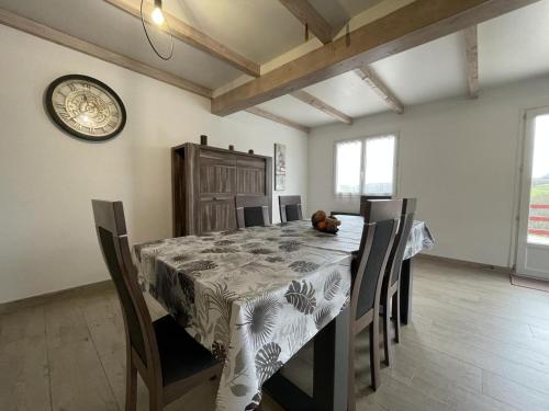 a dining room with a table and chairs and a clock at Pena plata in Sare