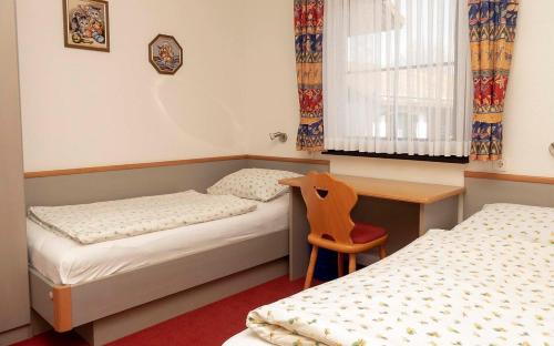 um quarto com 2 camas, uma secretária e uma cadeira em Ferienhaus Nr 72, Kategorie Komfort, Feriendorf Hochbergle, Allgäu em Bichel