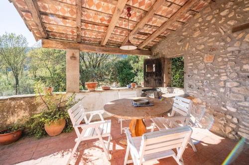 un patio con mesa, sillas y pared de piedra. en Cal Cisteller Argelaguer, en Argelaguer