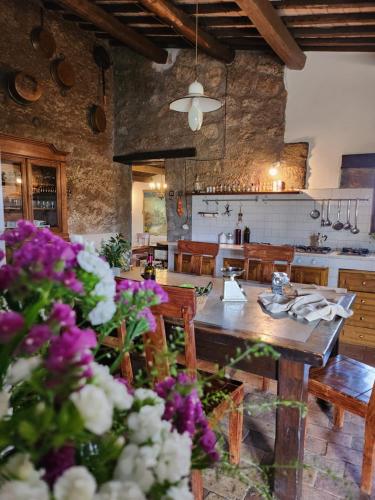 a kitchen and dining room with a table and purple flowers at Villa Arzilla Antica Residenza di campagna in Vitorchiano