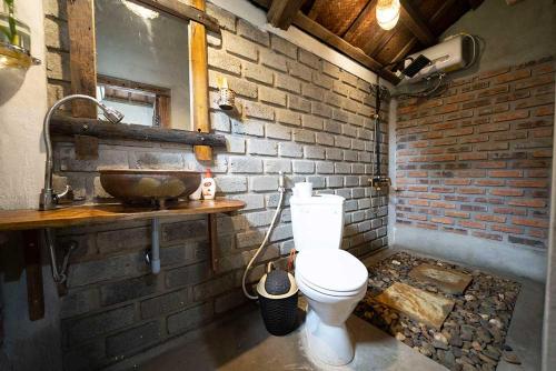 uma casa de banho com um lavatório e um WC numa parede de tijolos em Highway 20 Homestay em Dong Hoi