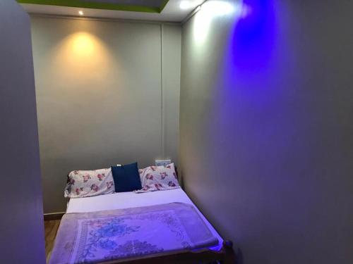 a small room with a bed with purple sheets and pillows at Sana Estate Stay in Madikeri