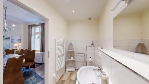 ein weißes Badezimmer mit einem Waschbecken und ein Esszimmer in der Unterkunft strandnahe FeWo mit Terrasse, Villa Vergissmeinnicht 01, Binz in Binz