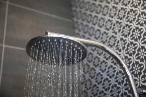 a shower with a shower head in a bathroom at Nightcap at Rex Hotel in Adelaide