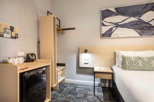 a hotel room with a bed and a desk and a bed at Nightcap at Rex Hotel in Adelaide