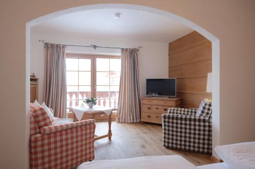 a living room with two chairs and a television at Hotel Maier zum Kirschner in Rottach-Egern