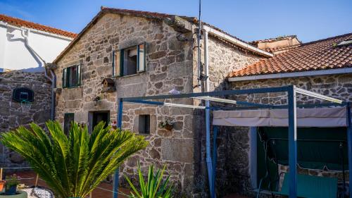 a stone house with a gate and a garage at Casa a Voada - Rural con Piscina Privada, Barbacoa y Juegos in Muiños