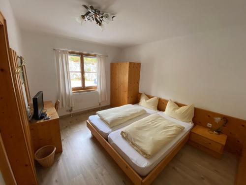 een slaapkamer met een bed met witte lakens en een raam bij Meilerhof in Reith bei Seefeld