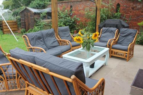 a patio with chairs and a couch and a table at The Walled Garden in Long Melford