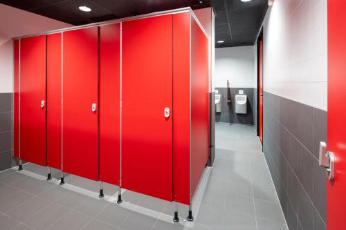 a row of red lockers in a bathroom with toilets at City Trip Hostels Zaandam-Amsterdam in Zaandam