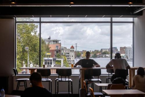 a group of people sitting at a bar with a large window at City Trip Hostels Amsterdam-Zaandam in Zaandam