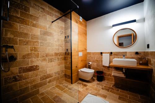 La salle de bains est pourvue de toilettes, d'un lavabo et d'un miroir. dans l'établissement Complexul Turistic Cheile Butii, à Cîmpu lui Neag