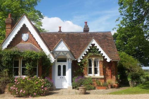 a small brick house with a clock on the roof at Gorgeous Country Cottage overlooking Windsor Castle in Old Windsor