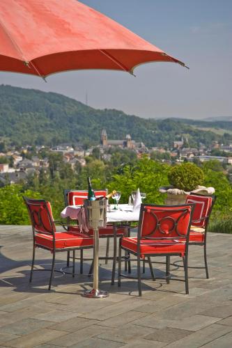 a table with red chairs and an umbrella at Eden au Lac in Echternach