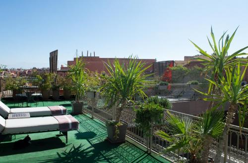 uma varanda com um sofá e algumas palmeiras em Riad Marana Hotel & Spa em Marrakech