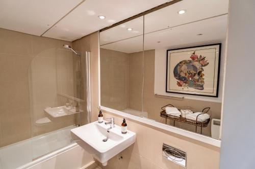 a bathroom with a sink and a mirror at Spacious West End Duplex Apartment, W1 Central London in London