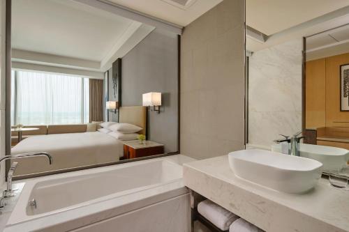 a bathroom with a bed and a tub and a sink at Batam Marriott Hotel Harbour Bay in Nagoya