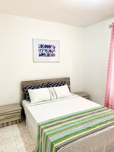 Un dormitorio con una cama blanca con una manta de colores. en Ariel Beach Apartment, en Flic en Flac