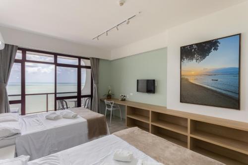 a hotel room with two beds and a television at Flat Edf Golden Beach in Recife