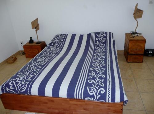Una cama con una manta azul y blanca. en chambres d'hôtes saint gilles les bains en Saint-Gilles-les-Bains