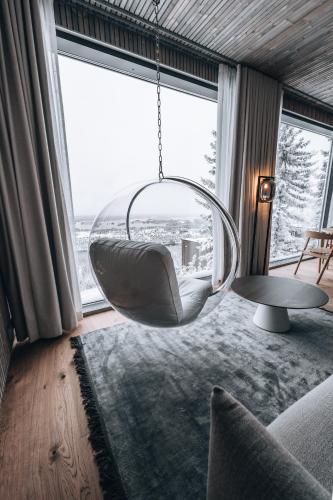 a hanging chair in a living room with a large window at Panorama Landscape Hotel in Nilsiä