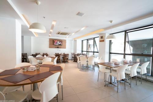 une salle à manger avec des tables et des chaises blanches dans l'établissement Promenade Prime Itaboraí, à Itaboraí