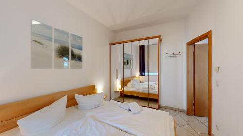 a bedroom with a bed with white sheets and a mirror at Villa Strandburg in Binz
