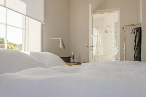 a white bedroom with a white bed and a window at Nordlandet in Allinge