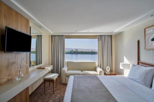 a hotel room with a large bed and a television at Mövenpick Royal Lotus Monday Four Nights Luxor Friday Three nights Aswan in Luxor