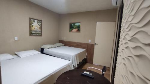 a small room with two beds and a table at Hotel Nacional in Sobral