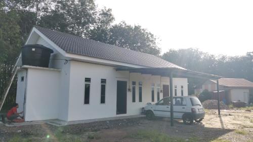 une voiture blanche garée devant une petite maison dans l'établissement Homestay D'kolam, à Pendang