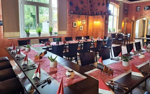 uma grande sala com mesas, cadeiras e janelas em Hotel Altes Badehaus em Bad Dürrenberg