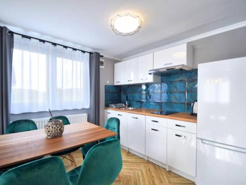 a kitchen with a wooden table and green chairs at Top Alex domki Międzyzdroje in Międzyzdroje