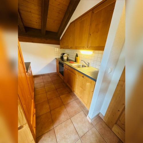 uma pequena cozinha com armários de madeira e um lavatório em Deluxe Penthouse in the Swiss Alps em Val dʼIlliez