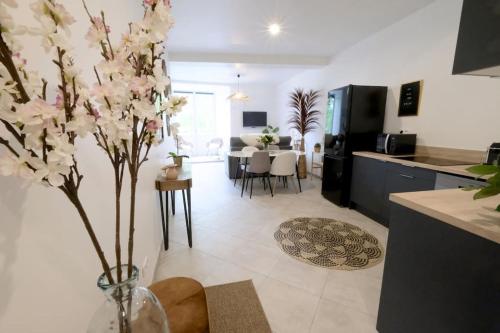 una cocina y una sala de estar con un jarrón con flores. en Lavilla dorée, en Moret-sur-Loing