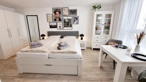 a white bedroom with a bed and a desk at Stadtgarten-Studios - im Zentrum mit Parkplatz in Weingarten