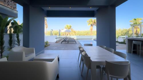 ein Restaurant mit Tischen und Stühlen und eine Terrasse in der Unterkunft Sunrise Beachfront Villas - Villa 3 in Paralimni